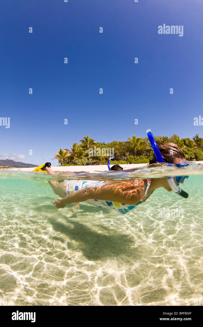 Giovane godendo lo snorkeling le chiare acque tropicali di una remota isola. Vicino a Beqa Lagoon, Beqa Island, Isole Figi Foto Stock