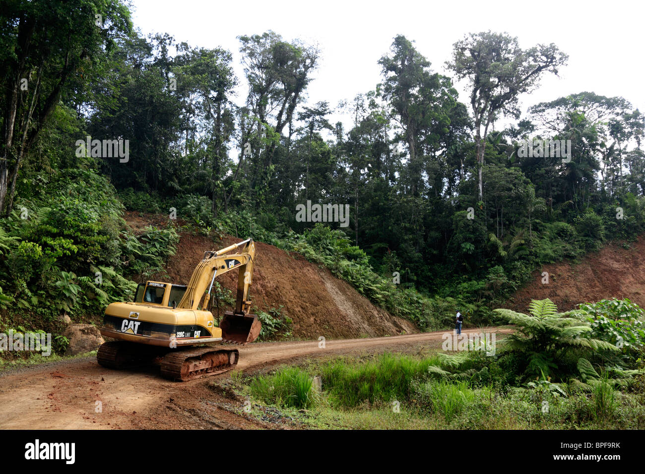Escavatore CAT 320C che lavora sulla nuova strada tagliata attraverso la foresta nebulizzata nella Comarca de San Blas fino a Carti, Panama Foto Stock