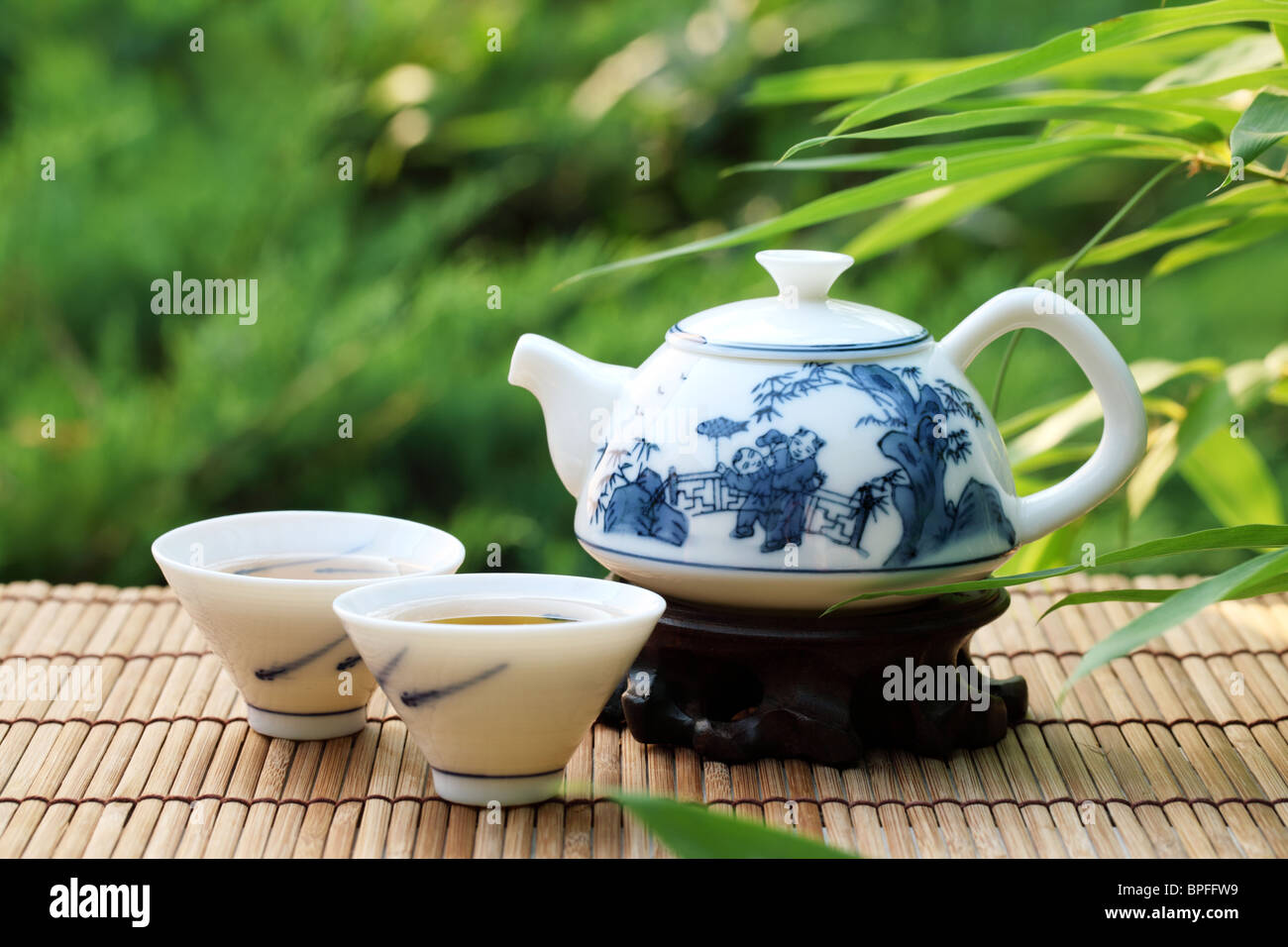 Teiera e tazze in pietra con foglie di bambù. Foto Stock