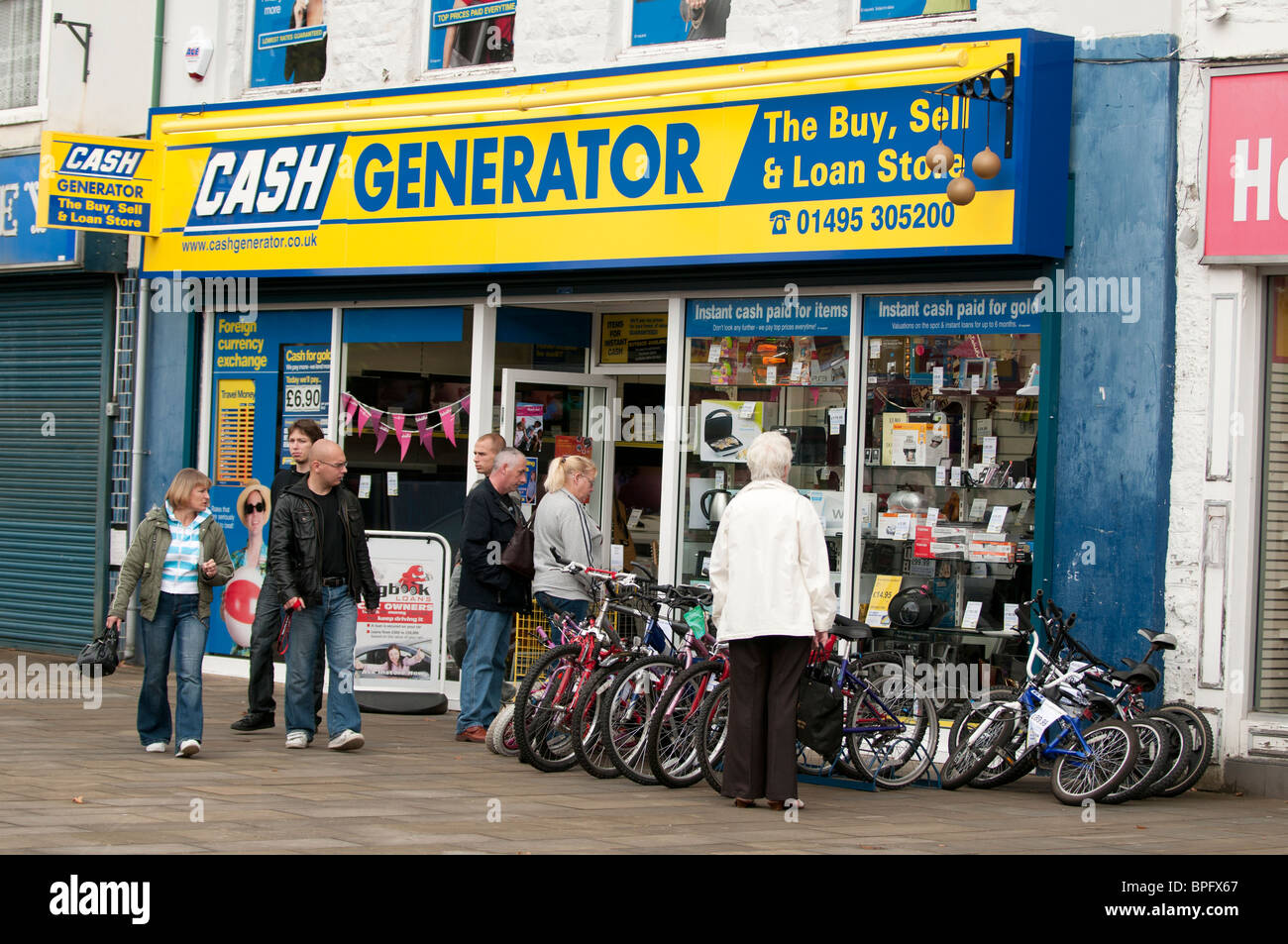 La gente di window shopping al di fuori del generatore di cassa high street comprare vendere e prestito pedina di franchising shop, Ebbw Vale, South Wales, Regno Unito Foto Stock