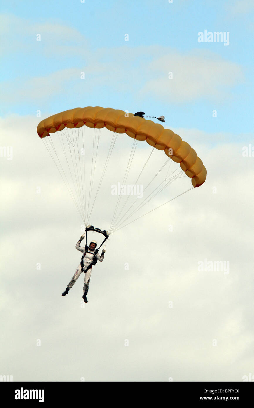 Femmina sky diver in bianco sotto un paracadute gialli Foto Stock