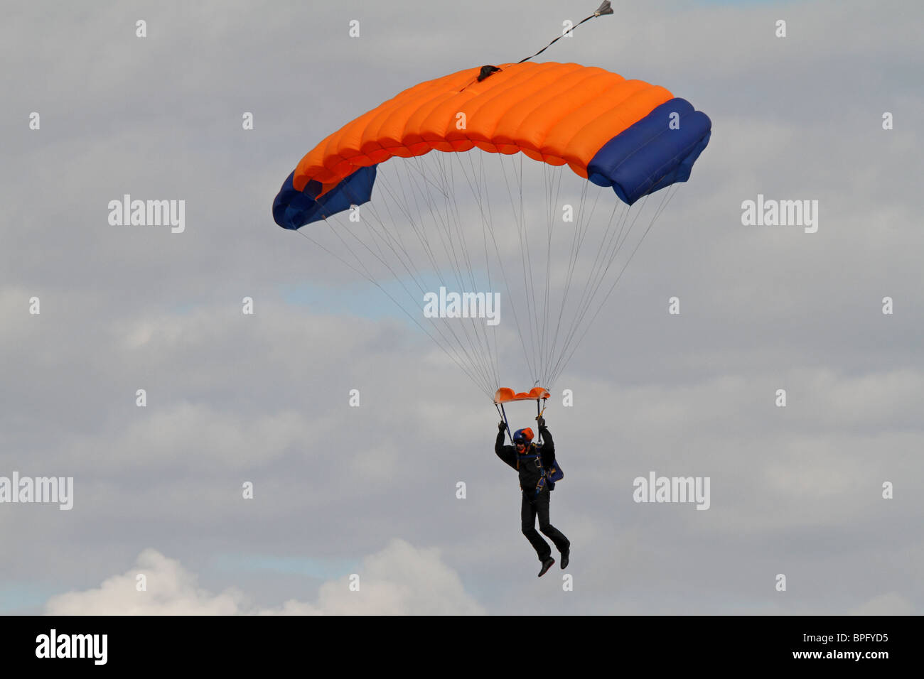 Paracadutista maschio sotto un paracadute arancione Foto Stock