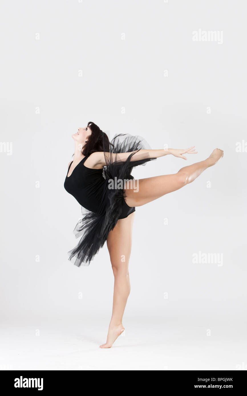 Bellissima ballerina femmina facendo split contro uno sfondo bianco Foto Stock