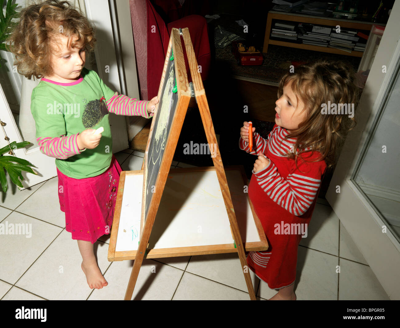 Le ragazze giovani sorelle di disegno con gesso sulla lavagna Foto Stock