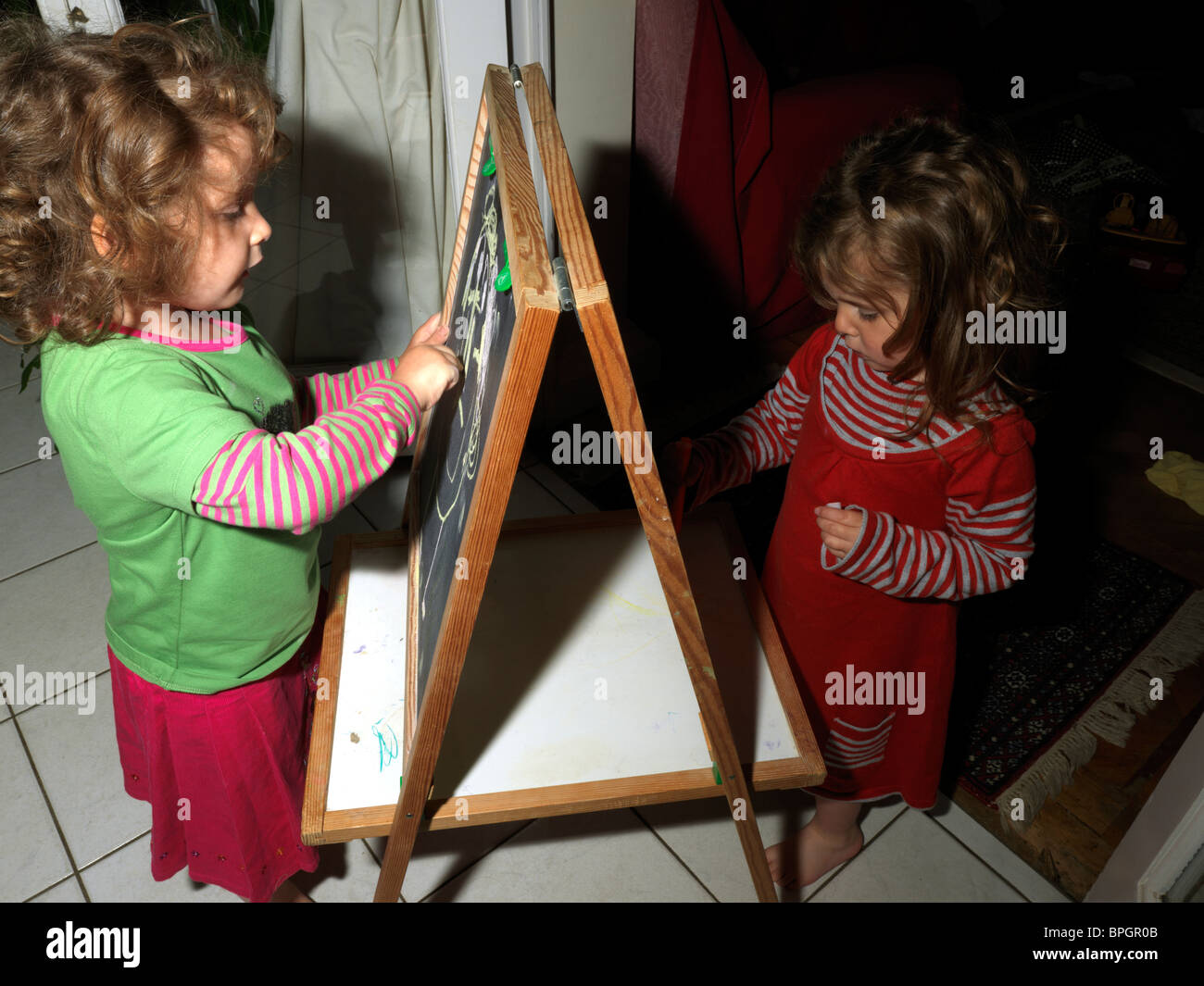 Le ragazze giovani sorelle di disegno con gesso sulla lavagna Foto Stock