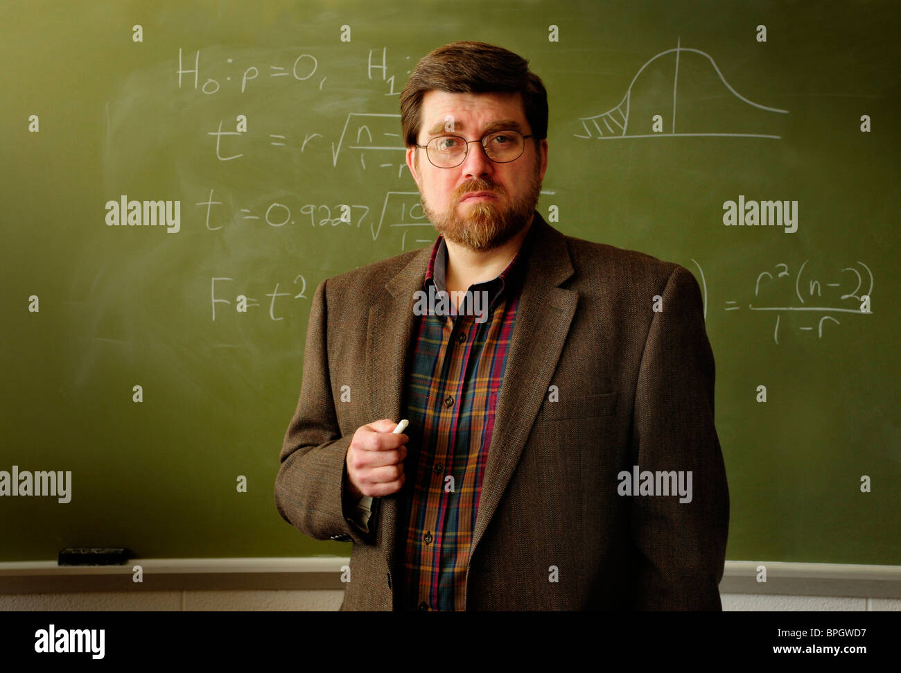 Professore di matematica o un insegnante in piedi in un'aula, formula statistica sulla lavagna verde in background. Foto Stock