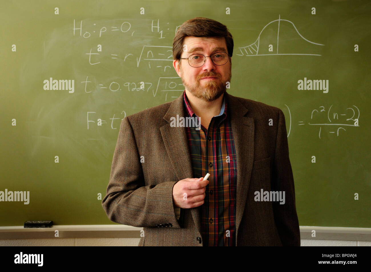 Professore di matematica o un insegnante in piedi in un'aula, formula statistica sulla lavagna in background. Foto Stock