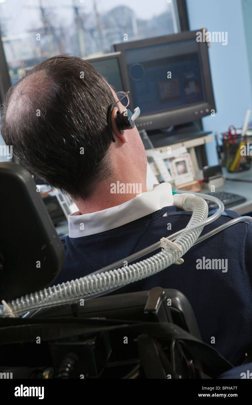 Imprenditore con distrofia muscolare di Duchenne utilizzando un ventilatore di respirazione in un ufficio Foto Stock