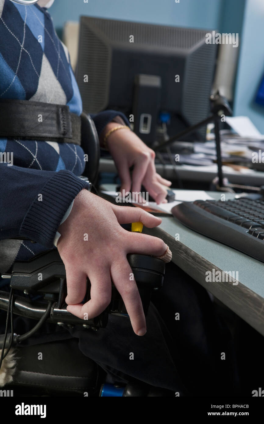 Imprenditore con distrofia muscolare di Duchenne in una sedia a rotelle motorizzata lavora in un ufficio Foto Stock