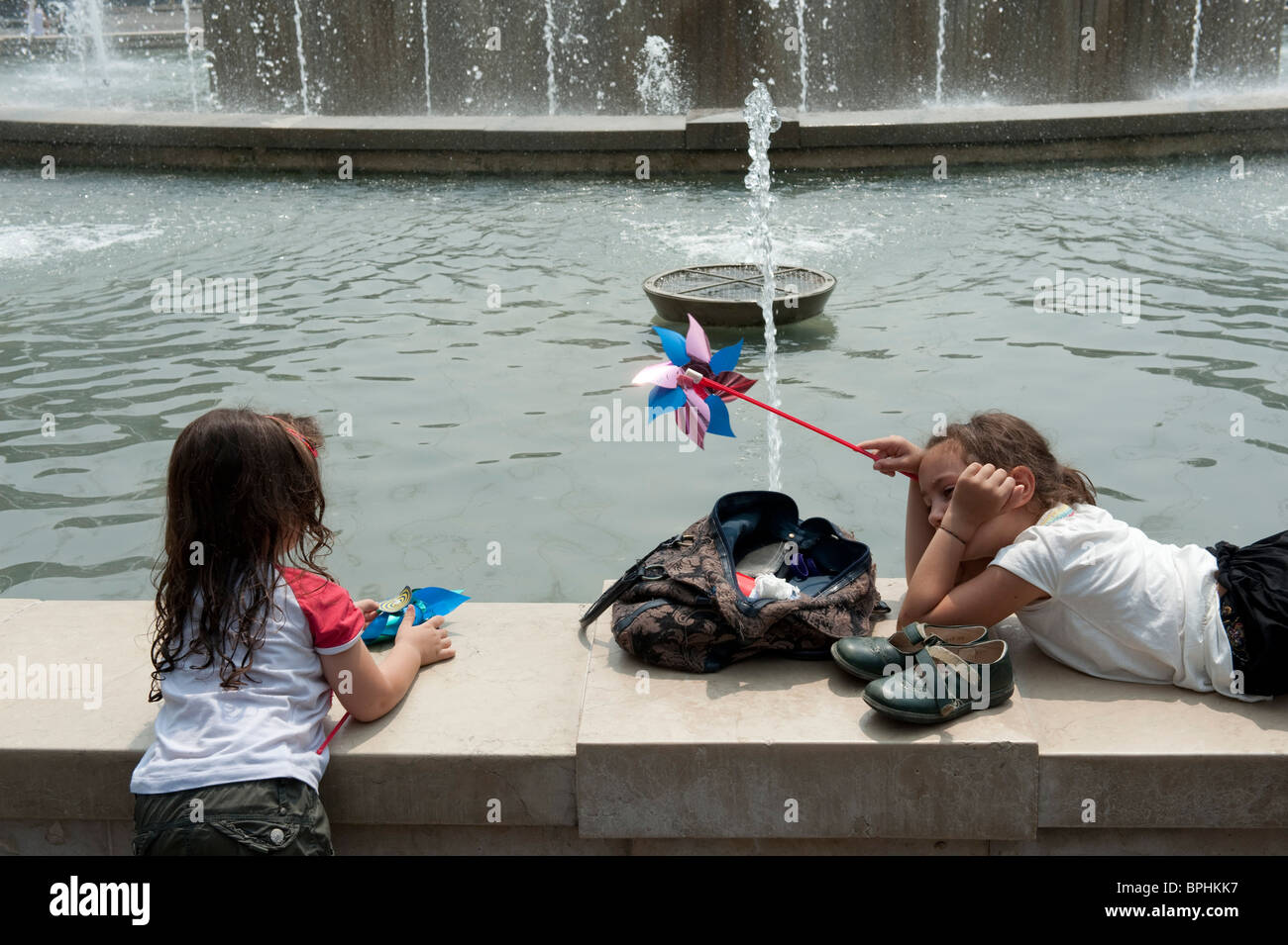 Due ragazze giocare su una fontana confine in una calda giornata estiva a Milano Italia Foto Stock