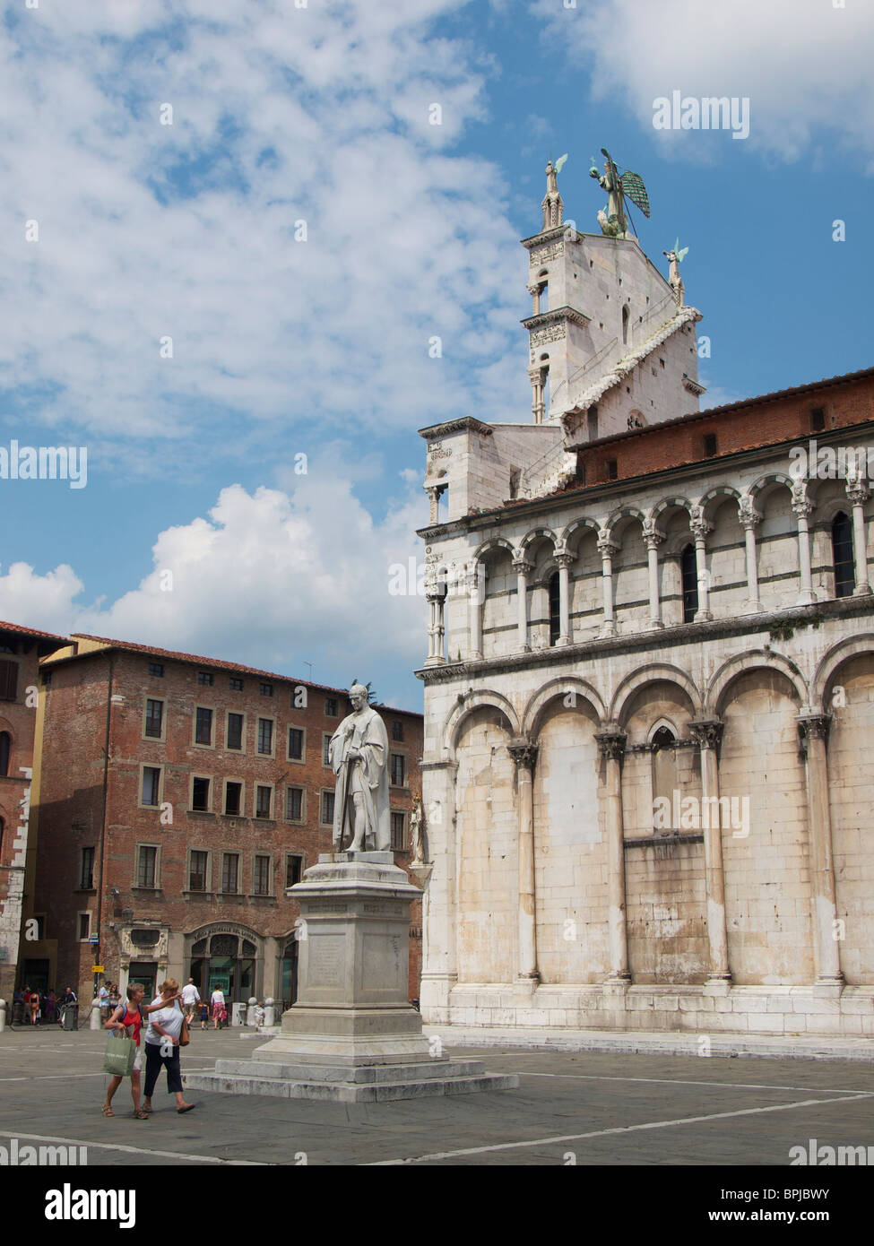 Chiesa di San Michele in Foro a Lucca, Toscana, Italia vista laterale con la statua e persone Foto Stock