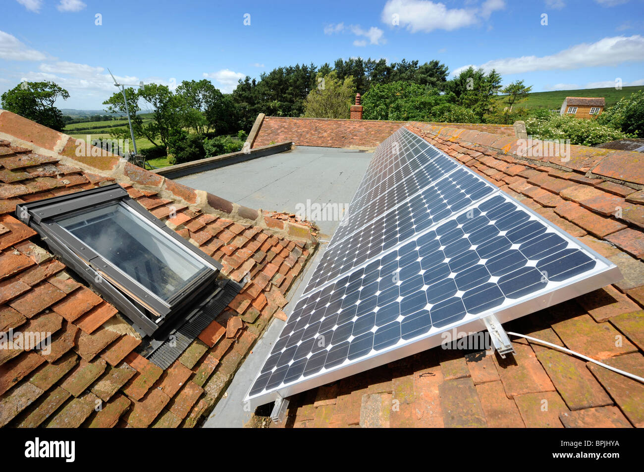 Foto-voltaico pannelli solari sul tetto di un eco-friendly home con una turbina eolica in giardino nel Buckinghamshire REGNO UNITO Foto Stock