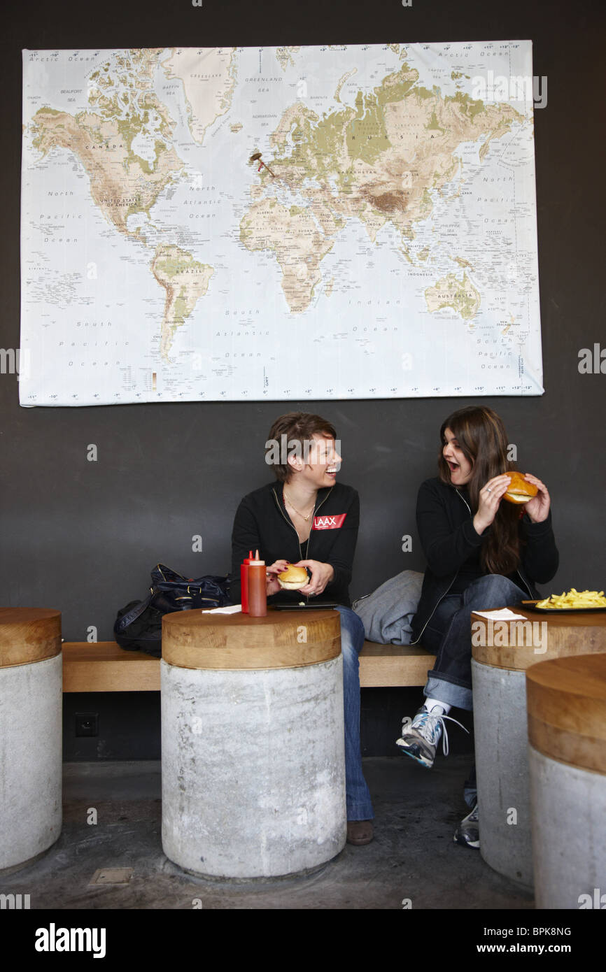 Due giovani donne mangiare hamburger in ristorante hamburger, Rocksresort, Laax del Cantone dei Grigioni, Svizzera Foto Stock