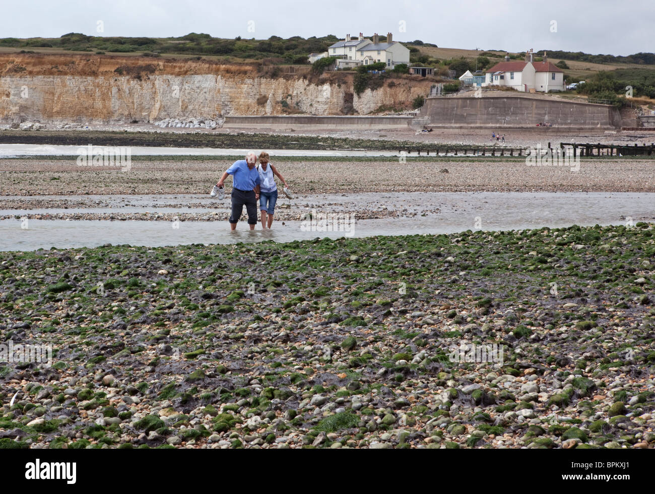 Due villeggiante sguazzare in acque poco profonde del Fiume Cuckmere a sette sorelle in East Sussex Foto Stock