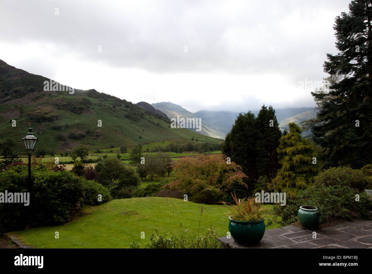 Guardando verso il basso grande Langdale valley da un giardino privato su un inizio di estate nebbiosa mattina nel Lake District inglese Foto Stock