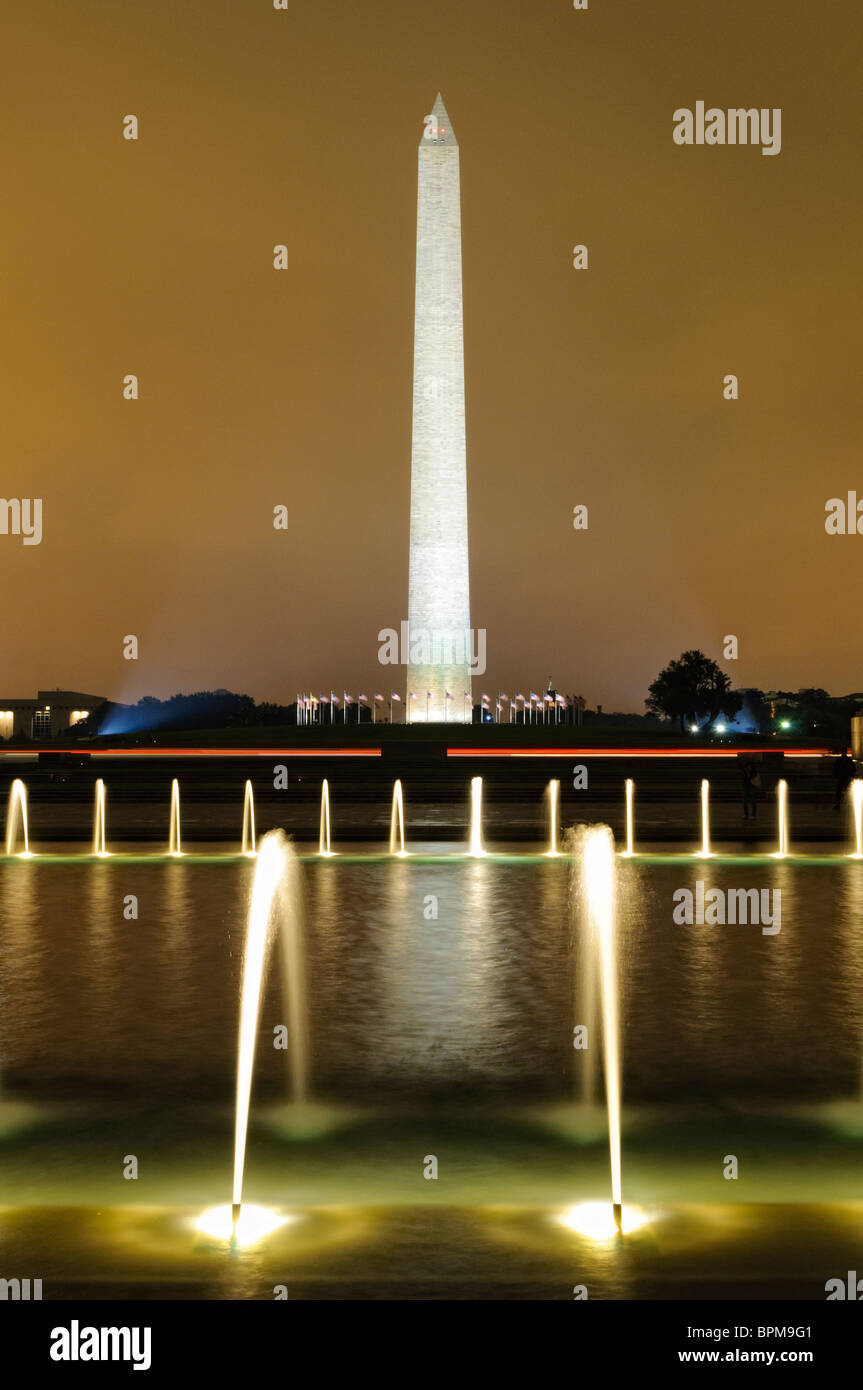 Washington Monument National Mall Fountain Washington DC // WASHINGTON DC - la fontana illuminata del National World War II Memorial sul National Mall di notte, con il Washington Monument visibile sullo sfondo. Il National World War II Memorial, dedicato nel 2004, onora i 16 milioni di americani che hanno prestato servizio nelle forze armate durante la seconda guerra mondiale e gli oltre 400.000 morti. Il memoriale presenta due archi di padiglioni che rappresentano i teatri della guerra atlantica e pacifica, collegati da una piazza centrale con la Rainbow Pool e la fontana. Monumento a Washington, completo Foto Stock