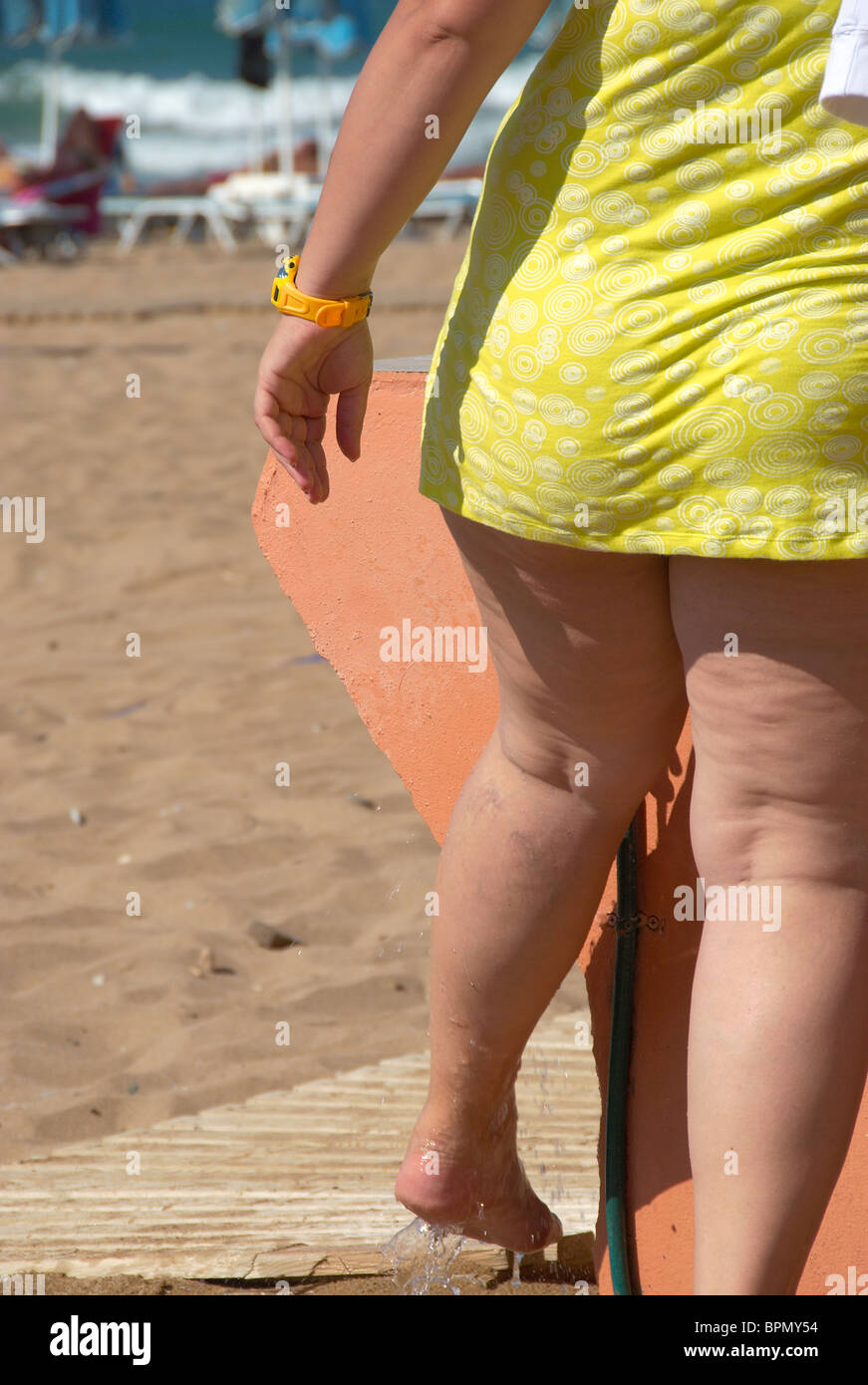 Il sovrappeso donna spiaggia di lavaggio della sabbia dai piedi Foto Stock