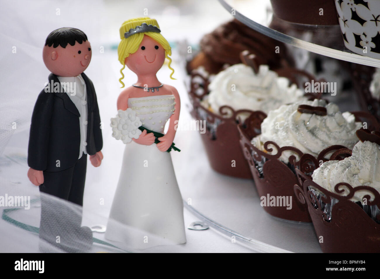 La sposa e lo Sposo cake topper accanto a una tortina moderno torta di nozze Foto Stock