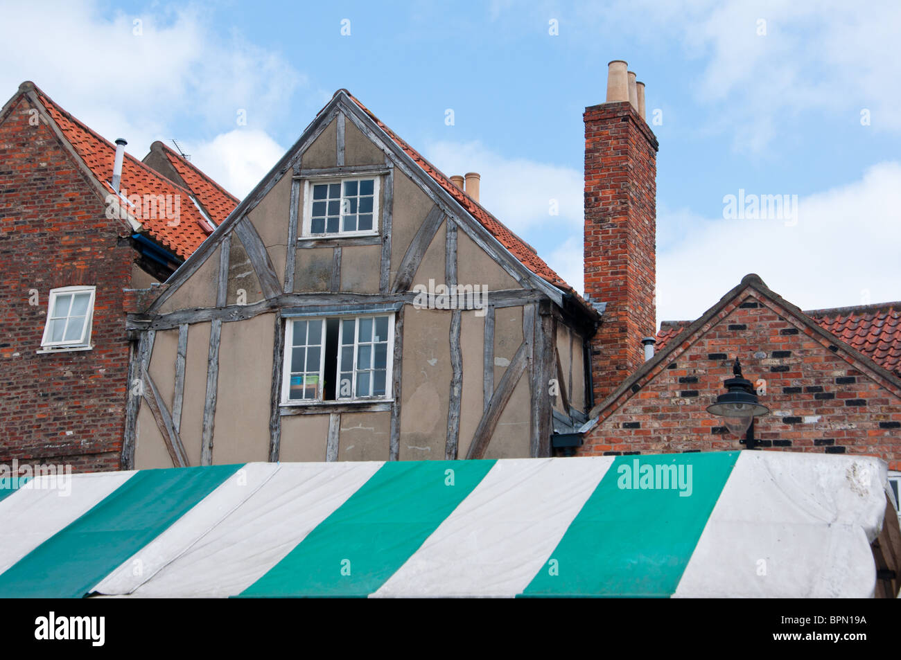 Gli edifici di vecchia costruzione sopra il baldacchino a strisce di York's Newgate market Foto Stock