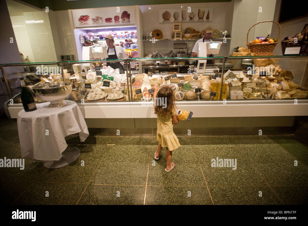 Una bambina, tenendo in mano un sacchetto di pasta alimentare secca, al contatore di formaggio a Eataly a New York Foto Stock