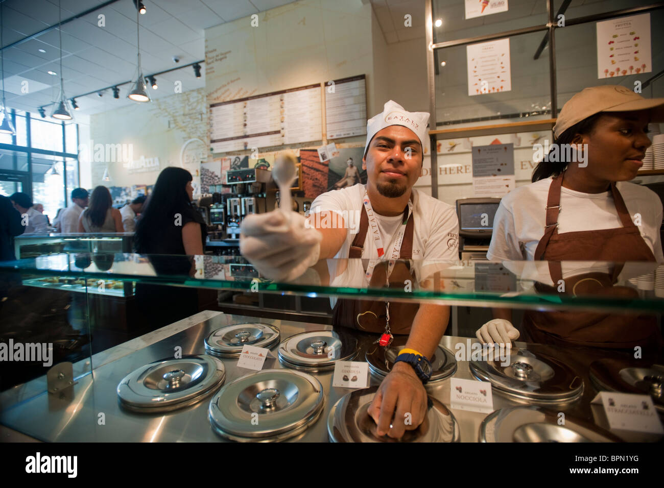 Un lavoratore offre un campione di gelato a Eataly a New York Foto Stock