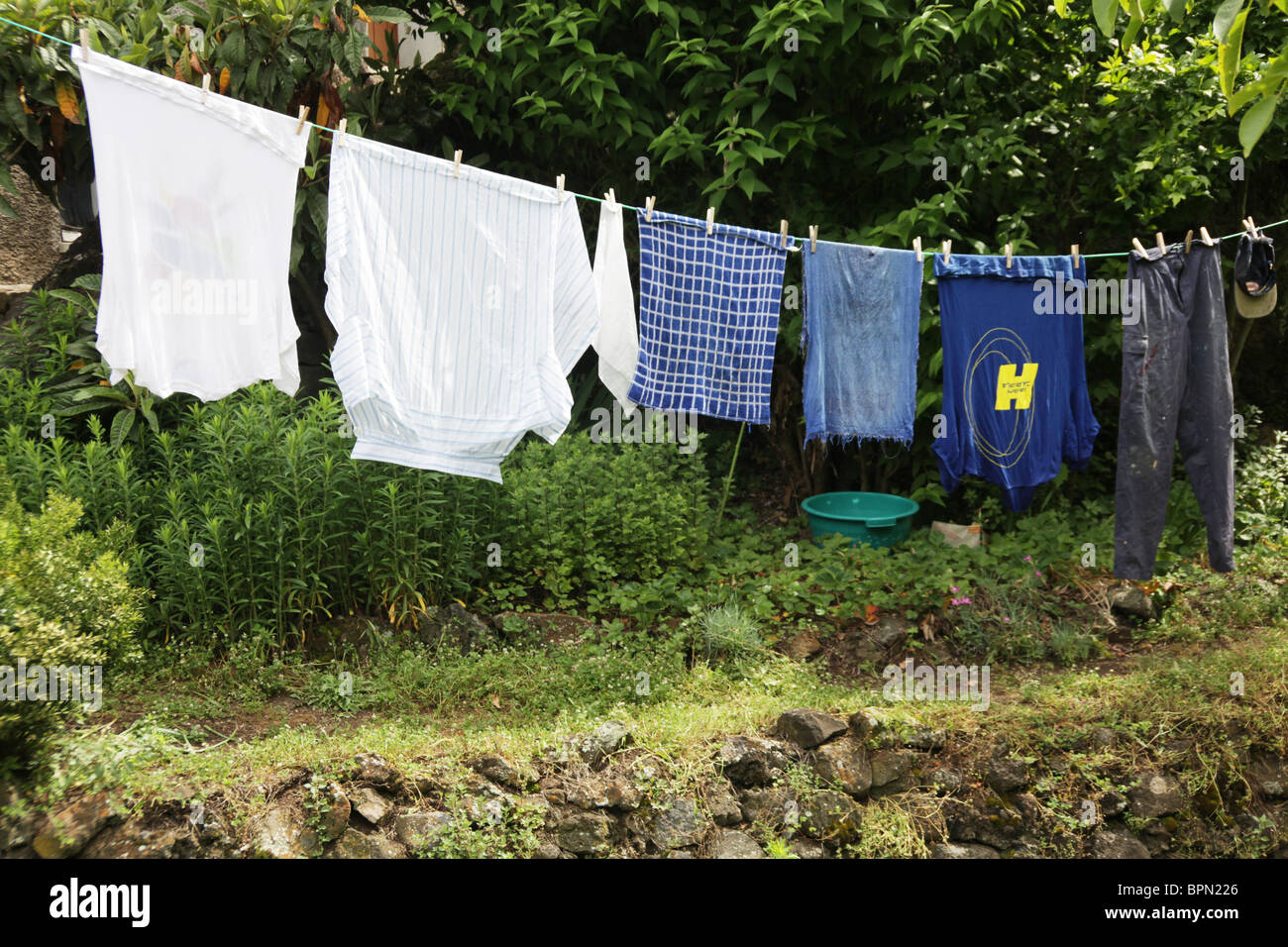 Una fattoria del lavoratore abiti da lavoro appesi su una linea di lavaggio in un cortile giardino Foto Stock