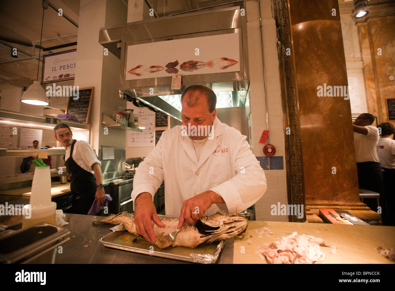 Un lavoratore si prepara a servire striped bass a Eataly artigianale il cibo italiano e vino marketplace in New York Foto Stock