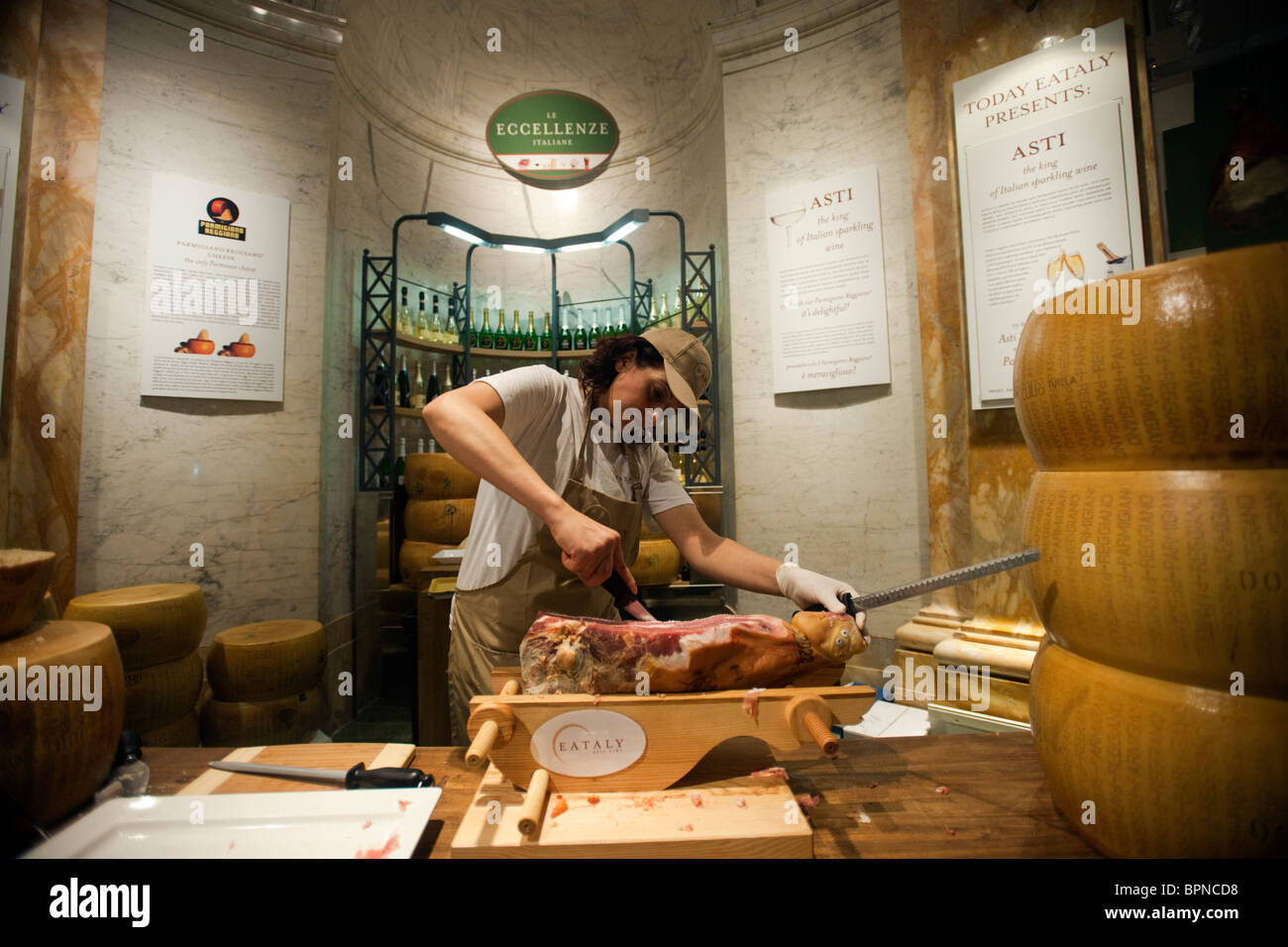 Un lavoratore fette di prosciutto a Eataly artigianale il cibo italiano e vino marketplace in New York Foto Stock