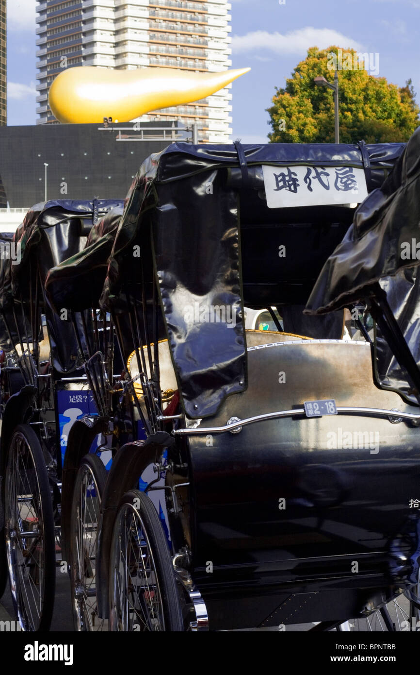 Giapponese carrelli di taxi di fronte al "fiamma" di Asahi Breweries, Sumida City, Tokyo, Giappone Foto Stock