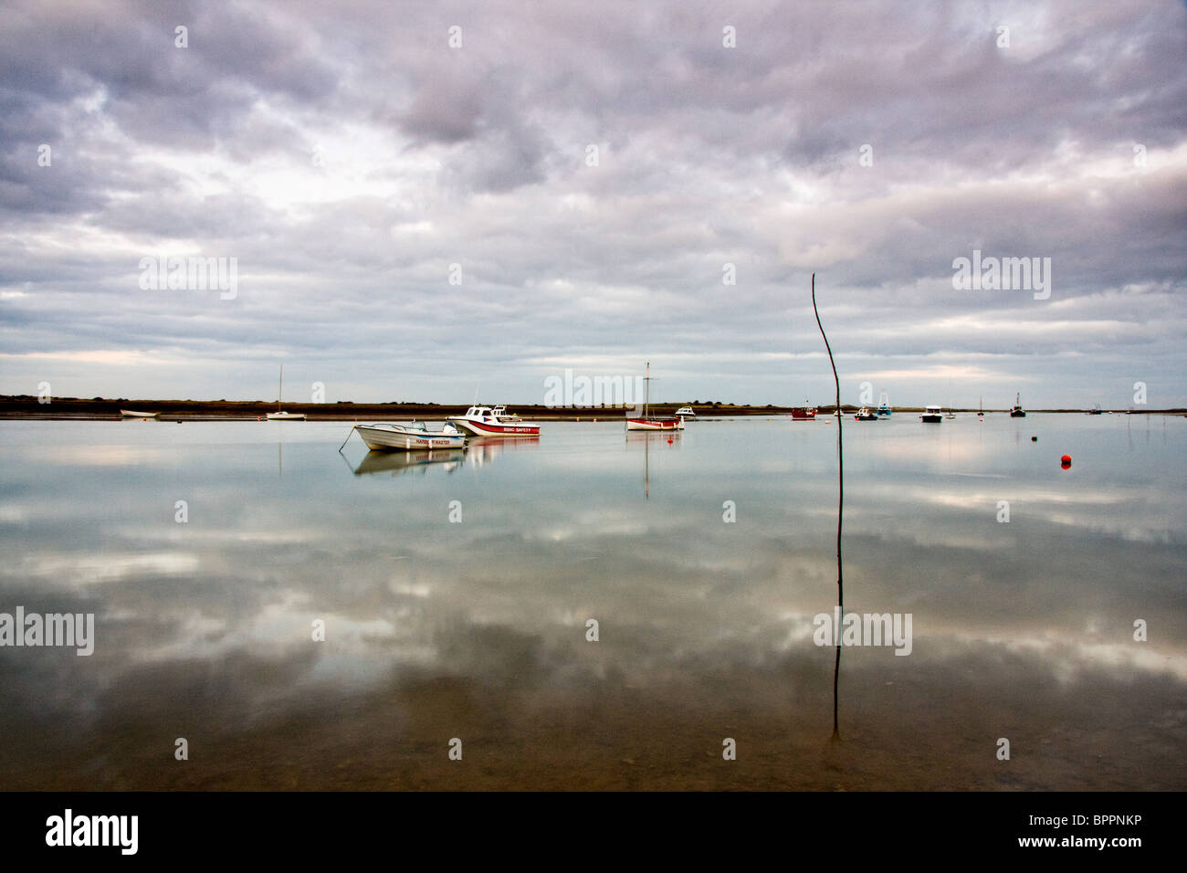 Prese a Brancaster Staithe in Norfolk estuario era ancora perfettamente e ha agito come uno specchio che riflette il cielo sull'acqua Foto Stock