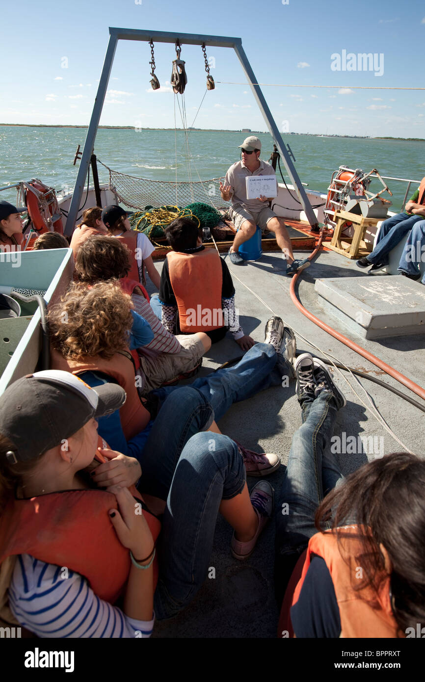 Gli studenti delle scuole medie ascoltano il biologo marino durante una gita sul campo a bordo di una nave di ricerca nel Golfo del Messico, appena fuori Corpus Christi, Texas Foto Stock