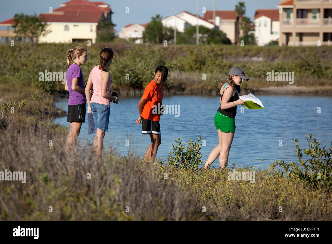 La scuola media di ragazze con il binocolo fare osservazioni, prendere appunti durante la biologia marina di campo classe di viaggio a Corpus Christi Bay Foto Stock