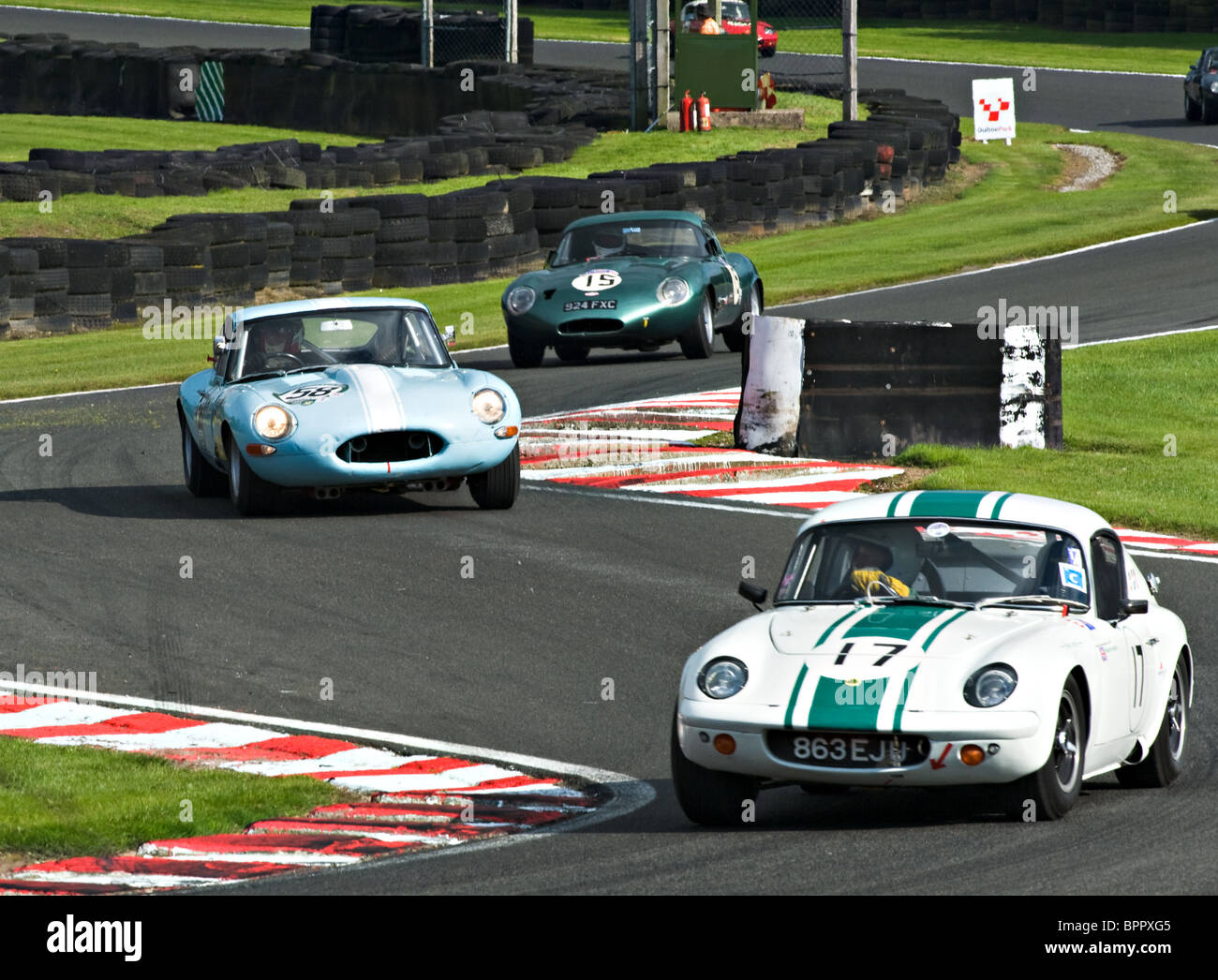 Lotus Elan seguita da due e type Jaguar auto da corsa negoziare Brittens ad Oulton Park Motor Racing circuito Cheshire England Regno Unito Foto Stock