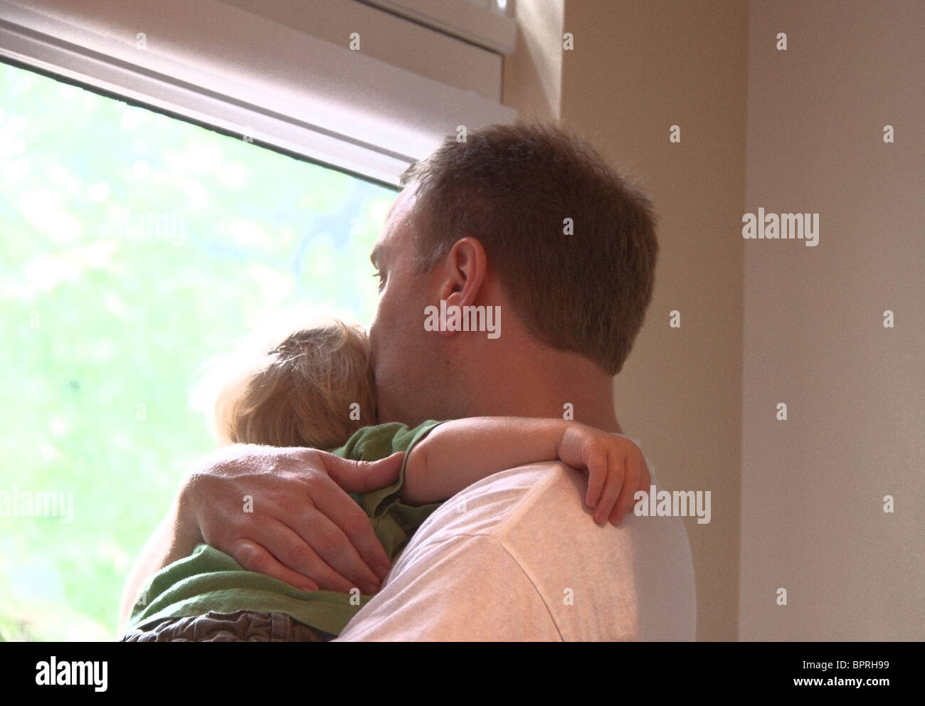 Padre e figlio guardando fuori dalla finestra in un giorno di pioggia Foto Stock