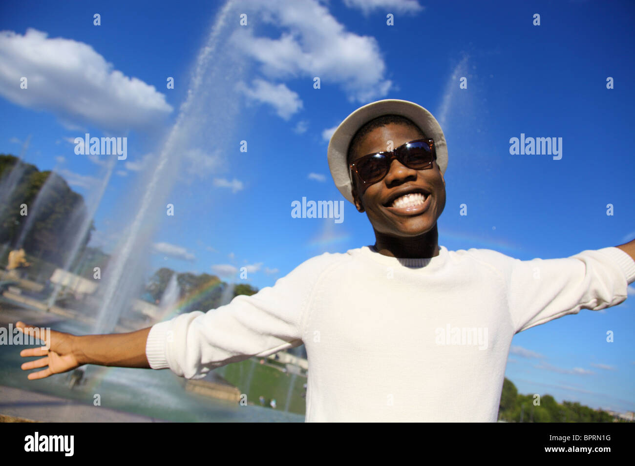 Giovane uomo sorridente con i bracci aperti in una giornata di sole Foto Stock