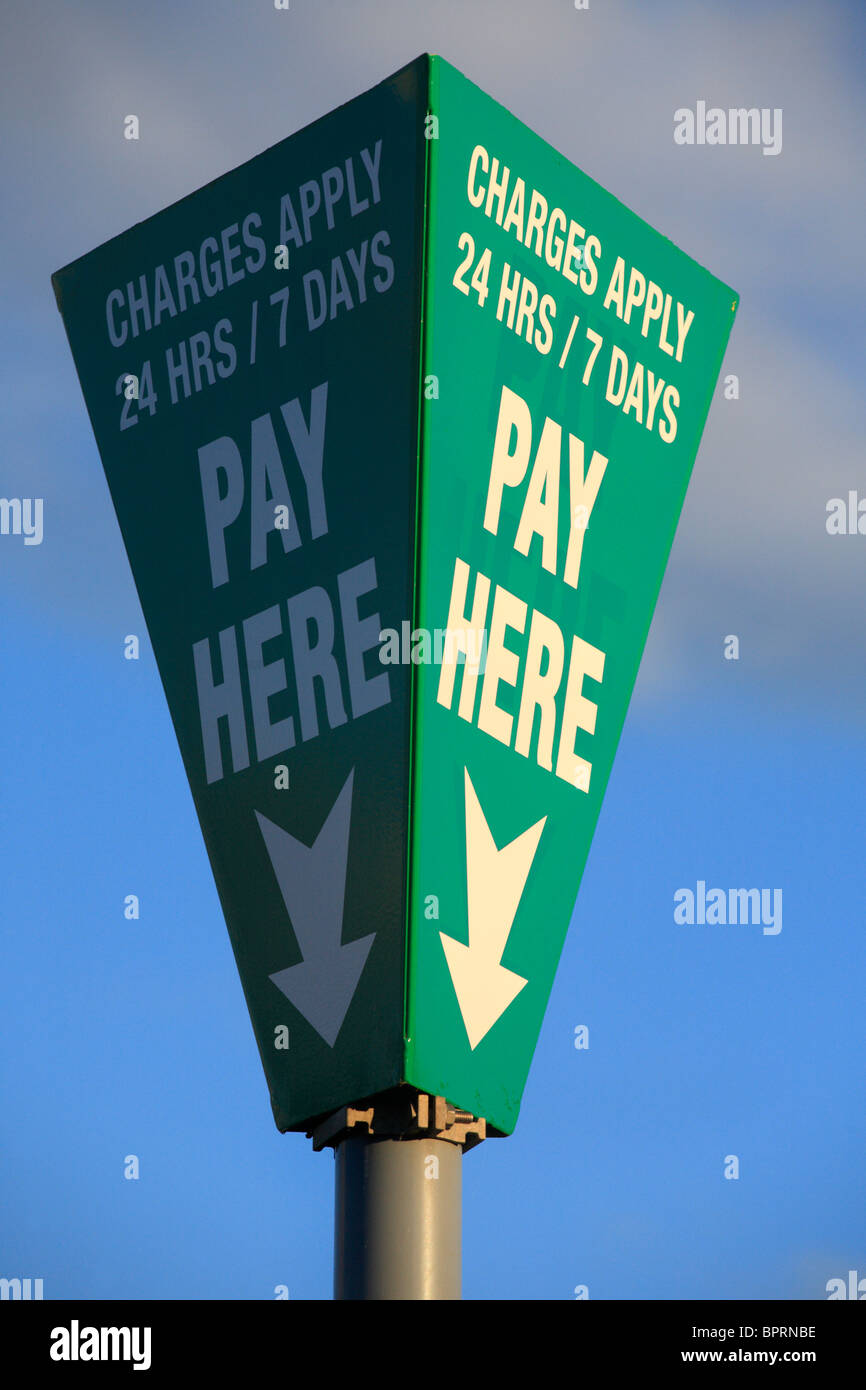 Segno posto in un parcheggio che indica dove pagare e che le tariffe si applicano 24/7. Foto Stock