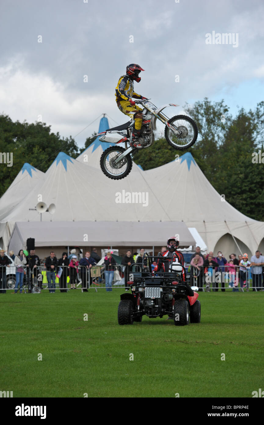 Motociclo stuntman vola in aria sopra la testa di un altro stunt man come la folla guarda lui a una mostra di estate Foto Stock