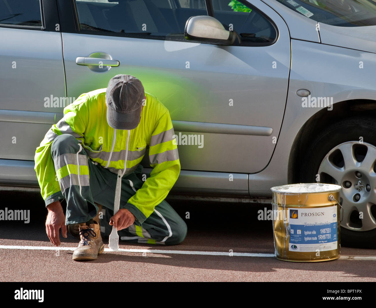 Consiglio pittura del lavoratore la linea bianca nel parcheggio auto bay - Francia. Foto Stock