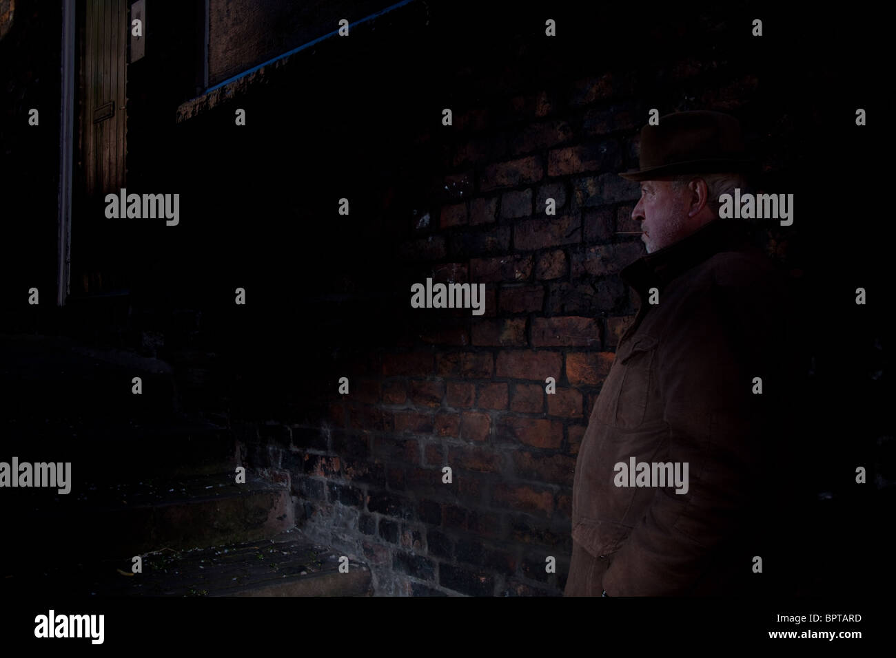 Film Noir raffigurante una tranquilla e uomo pericoloso in attesa in un vicolo scurito. Foto Stock