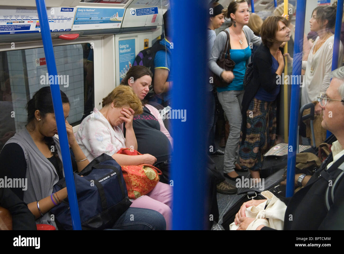 Donna incinta stanco ed esausto. La metropolitana di Londra di passeggeri. Affollata tenendo la testa nelle mani di lei è usurata Londra treno tubo UK 2010s HOMER SYKES Foto Stock