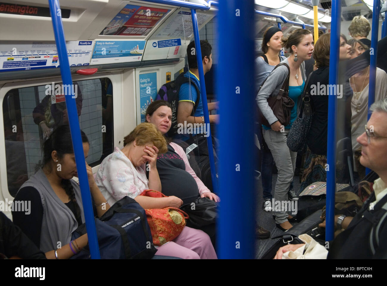 Stanca ed esausta, donna con la testa in mano, seduta accanto a una donna incinta stanca su un affollato treno della metropolitana di Londra. 2010 2010 UK HOMER SYKES Foto Stock