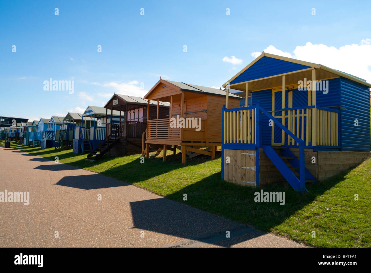 Fila di whitstable cabine sulla spiaggia, gettato ombre lunghe Foto Stock