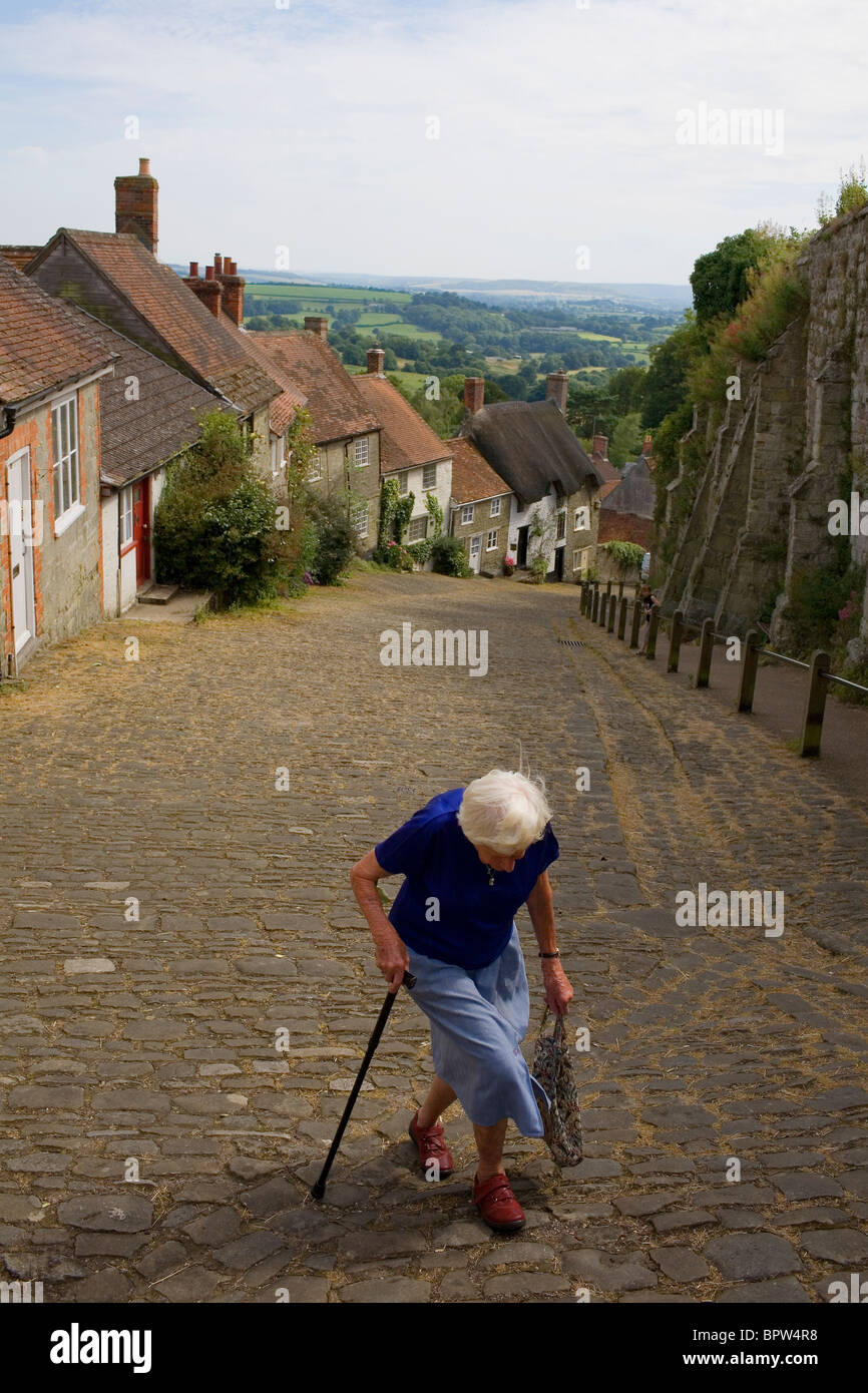 Una vecchia donna cammina verso la cima della collina d'oro in Shaftesbury, Dorset. Foto Stock