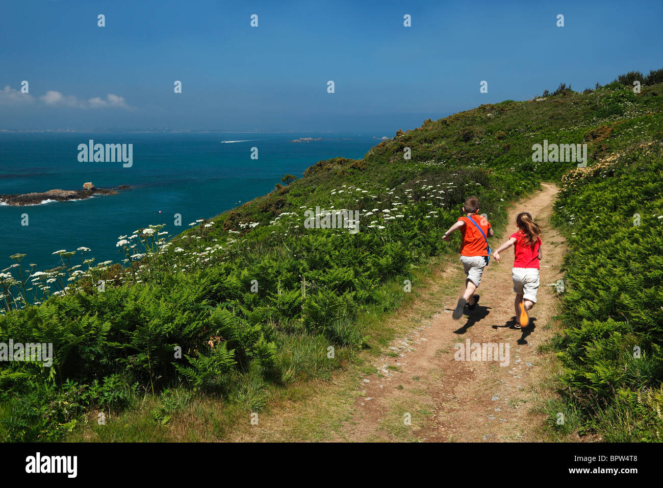 Due bambini gara eccitato lungo il sentiero costiero di Herm nelle isole del Canale di Inghilterra Foto Stock