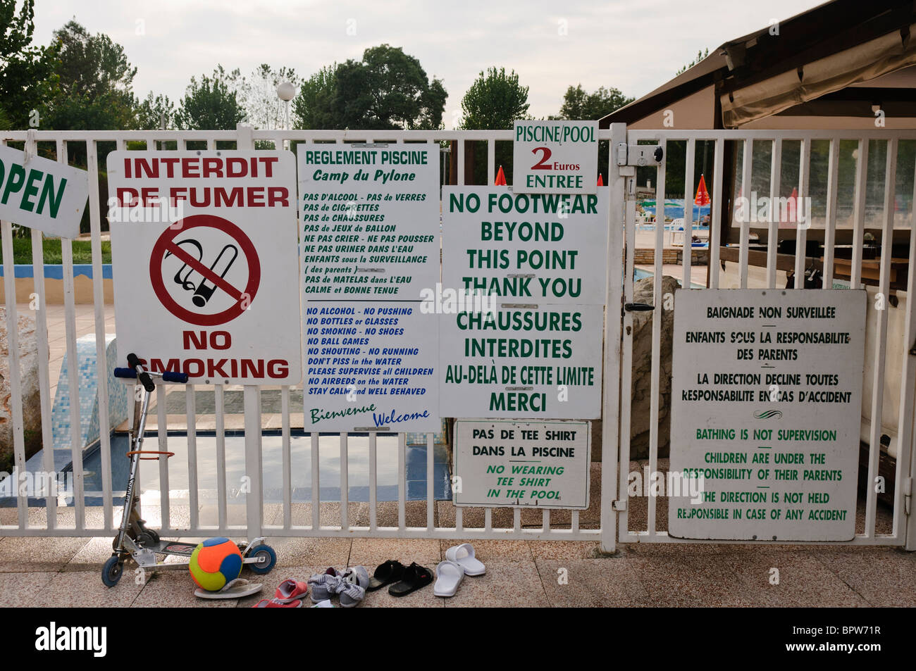 Moltitudine di bilingue segnaletica di avvertimento e le regole all'entrata di una piscina in Francia Foto Stock