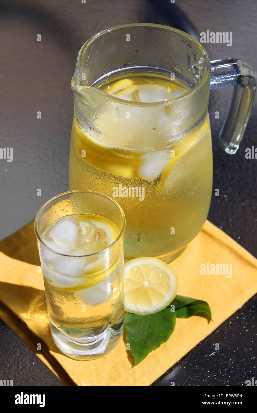 Brocca di emonade nel vasetto di vetro e con i limoni, ghiaccio sul tavolo per esterno Foto Stock