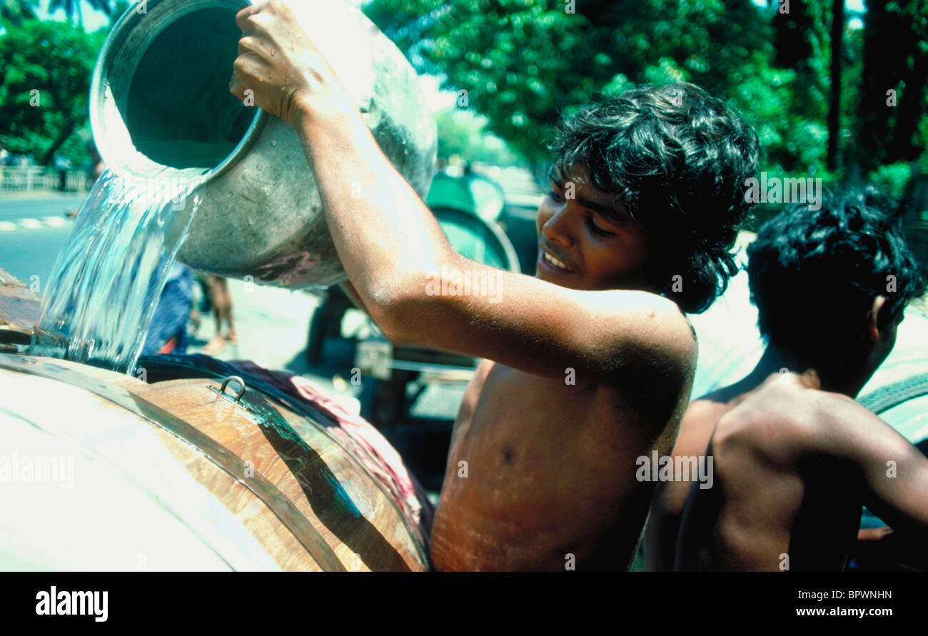 Un giovane portatore d'acqua che riempie a mano un serbatoio a Mumbai, India Foto Stock