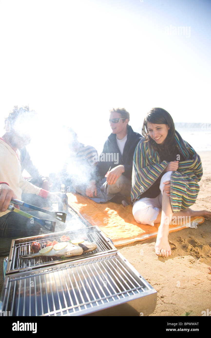 Gruppo di amici seduti intorno a un falò sulla spiaggia Foto Stock