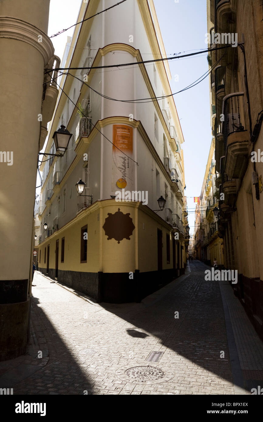 Tipico tradizionale spagnolo torna in ciottoli street / strade / strada lungo con angolare edifici e cielo blu. Cadiz, Spagna. Foto Stock