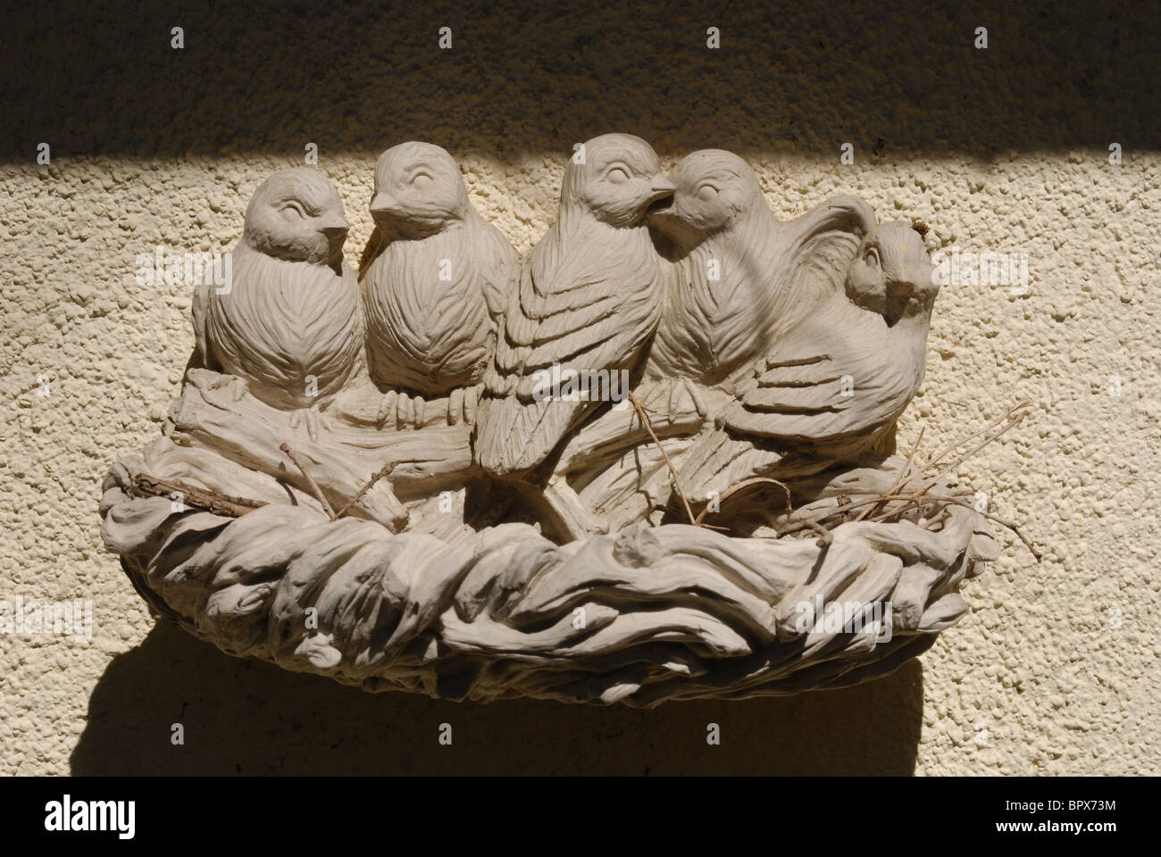 Una decorativa Bagno uccelli montato su di un lato della parete da giardino Foto Stock